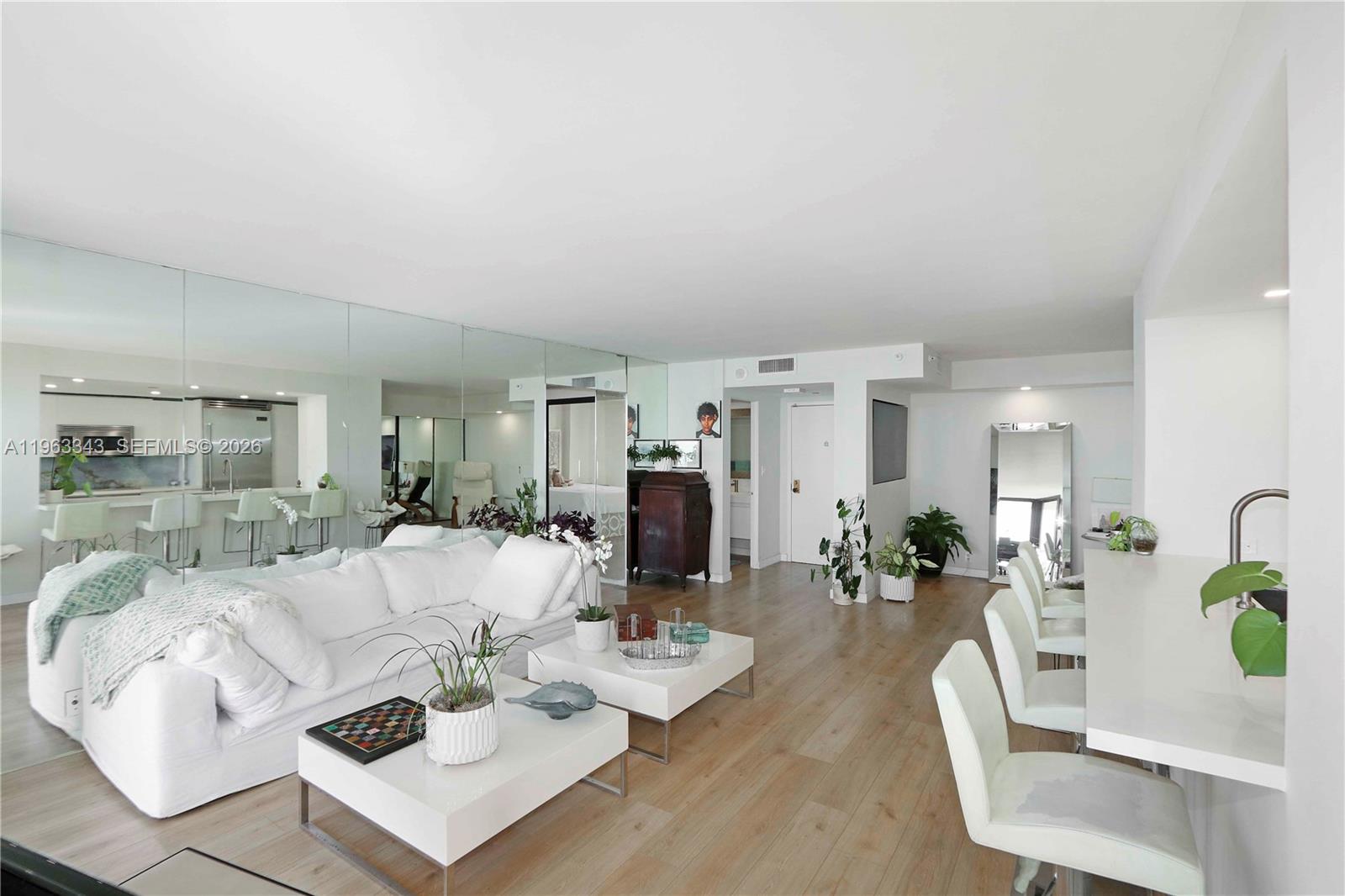 A living room features a white sofa, two coffee tables, and a mirrored wall — 1000 Quayside Ter # 1608, Miami FL 33138, MIAMI, FL