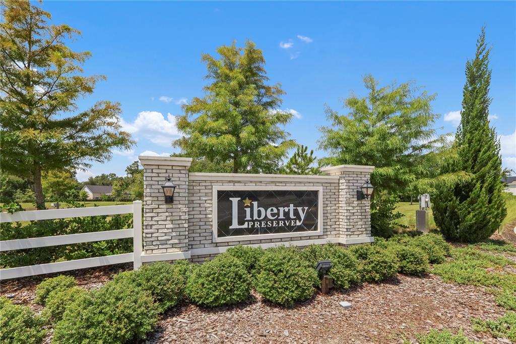A brick monument sign for Liberty Preserve stands in a landscaped area with trees — 33571 SKY BLOSSOM CIRCLE, LEESBURG, FL