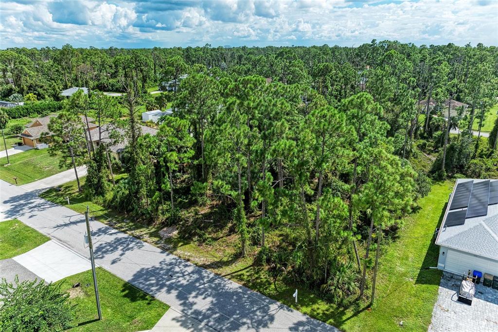 An aerial view shows a vacant, wooded lot situated between two residential houses — 1139164804, 1139164805 FOXGLOVE AVENUE Lot 4, lot 5, NORTH PORT, FL