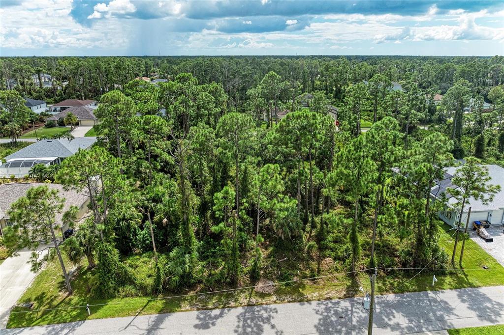An aerial view shows a vacant, wooded residential lot situated between two existing houses — 1139164804, 1139164805 FOXGLOVE AVENUE Lot 4, lot 5, NORTH PORT, FL
