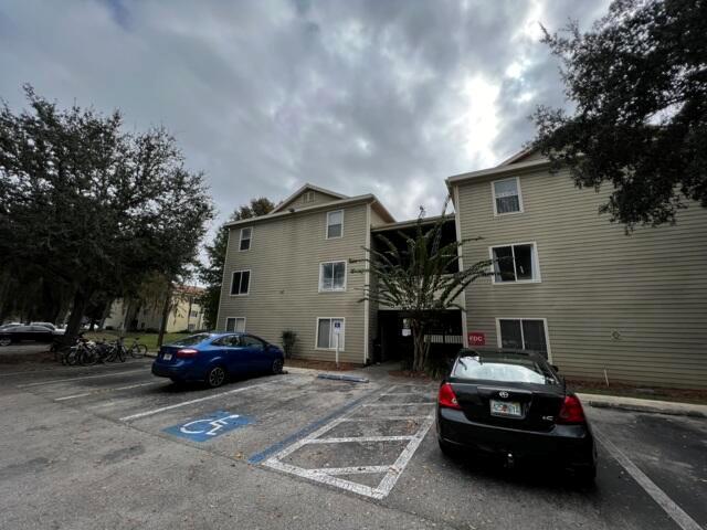 Exterior view of a three-story apartment building with parking spaces and a handicap spot — 3800 SW 20th Avenue # 305, Gainesville FL 32607, GAINESVILLE, FL
