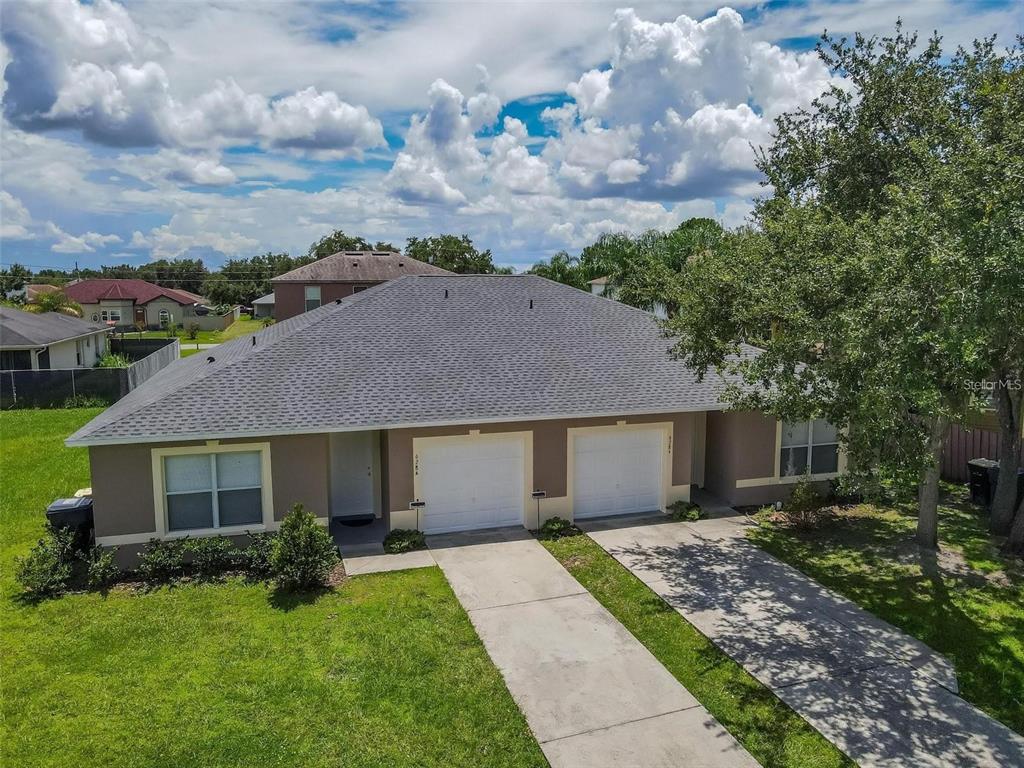 An aerial view of a single-story duplex with two garages and a gray shingled roof — 628 BLUEBILL COURT, POINCIANA, FL