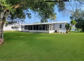A single-story house with a screened-in porch sits on a large, grassy lawn — 1047 Mayford Lake Rd, Moore Haven FL 33471, MOORE HAVEN, FL