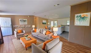 A living room features light wood flooring, a gray sofa, and an orange ottoman — 1047 Mayford Lake Rd, Moore Haven FL 33471, MOORE HAVEN, FL