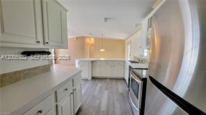 A kitchen features white cabinets, light countertops, stainless steel appliances, and wood-look flooring — 1047 Mayford Lake Rd, Moore Haven FL 33471, MOORE HAVEN, FL