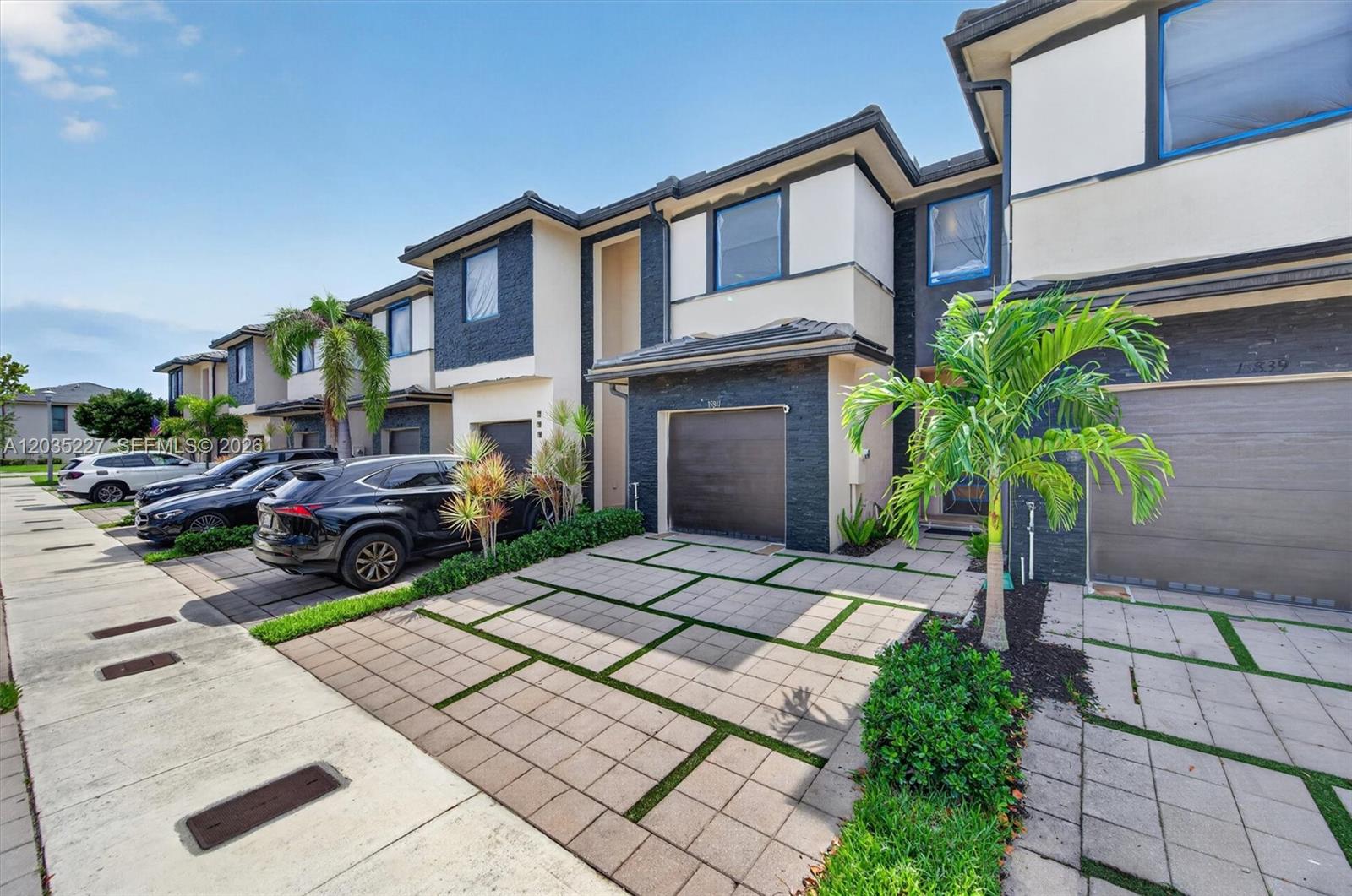 A row of modern townhouses features dark stone accents, paved driveways, and attached garages — 15841 NW 91st Ct, Miami Lakes FL 33018, MIAMI LAKES, FL