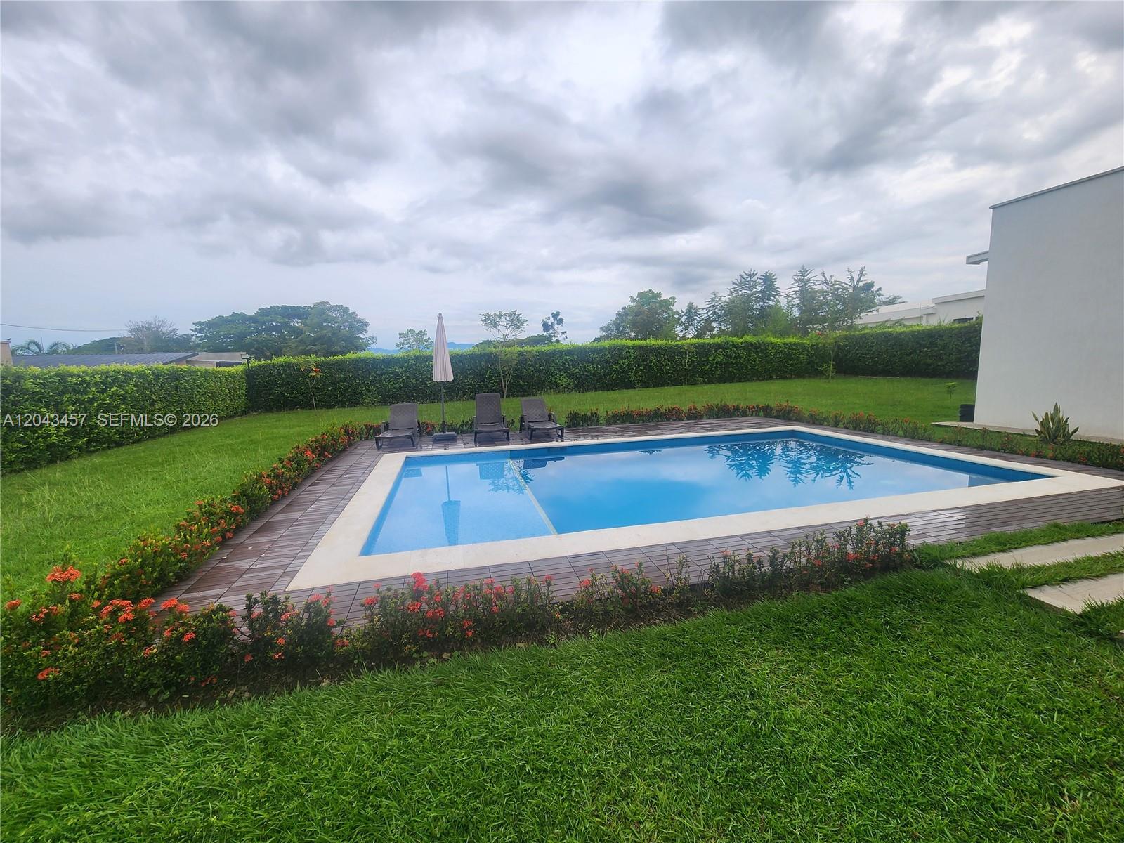 A rectangular swimming pool with a wooden deck is surrounded by a lawn and hedges — 0 GINEBRA VALLE COL, FL, FL
