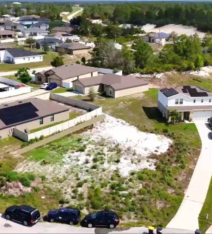 An aerial view shows a vacant residential lot situated between several suburban houses — 17 LARCH LANE, KISSIMMEE, FL