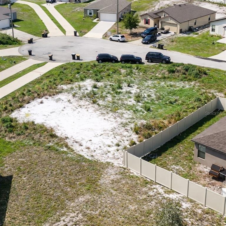 An aerial view shows a vacant residential lot next to a fenced house and street — 17 LARCH LANE, KISSIMMEE, FL