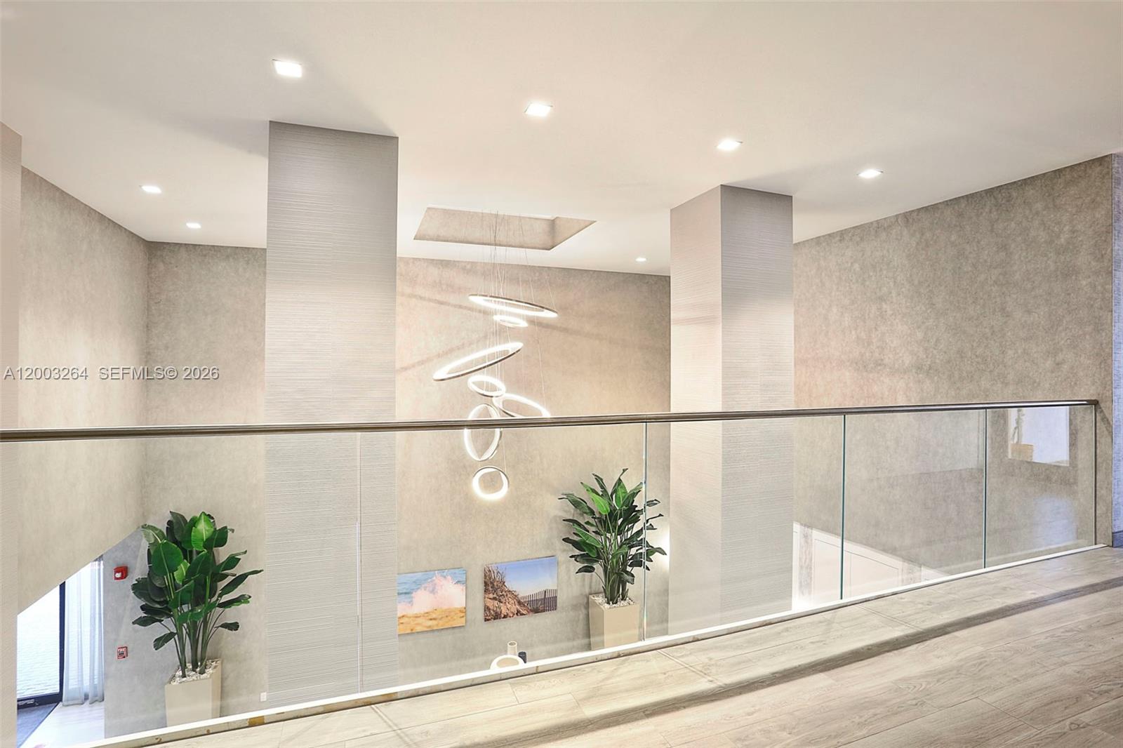 A modern interior hallway features a glass railing, textured walls, and a sculptural ring chandelier — 2301 S Ocean Dr # 1705, Hollywood FL 33019, HOLLYWOOD, FL