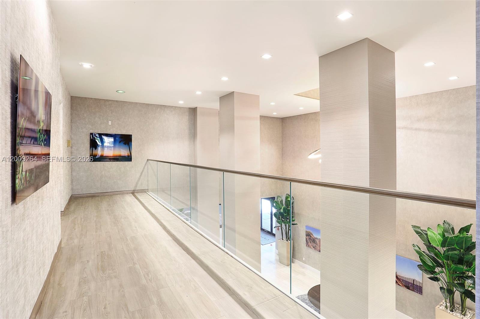 A modern indoor balcony overlooks a lower level with glass railings and light wood flooring — 2301 S Ocean Dr # 1705, Hollywood FL 33019, HOLLYWOOD, FL