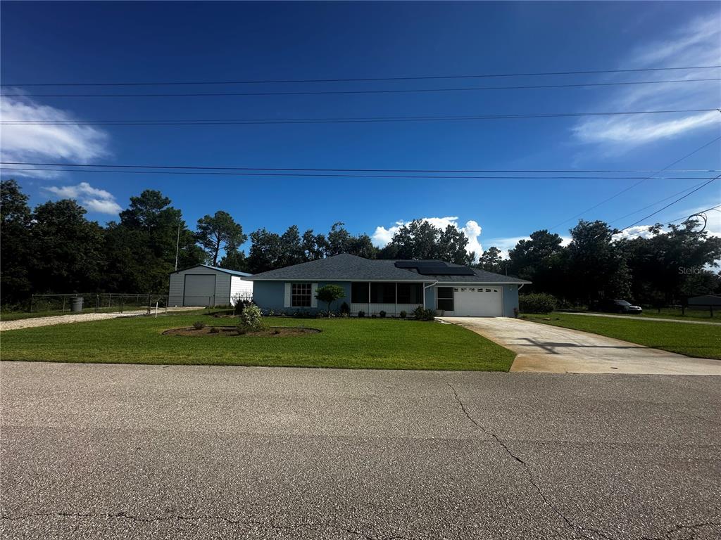 A light blue single-story house with a detached garage and a concrete driveway — 5005 GRAND CONCOURSE, SEBRING, FL
