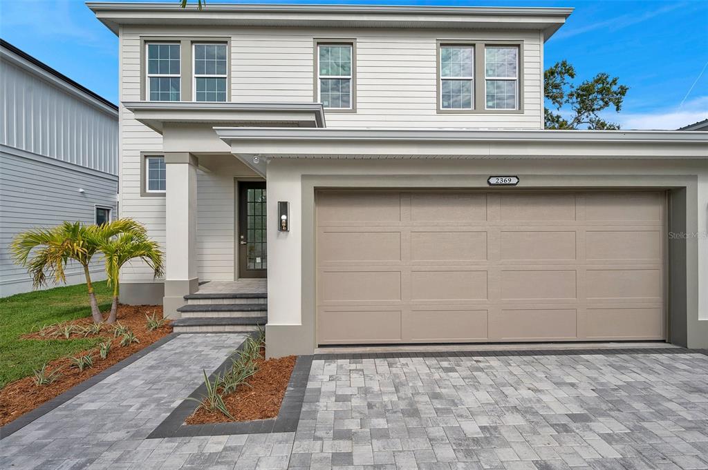 A two-story house features white horizontal siding, a beige garage door, and a paved walkway — 2369 BAHIA VISTA STREET, SARASOTA, FL