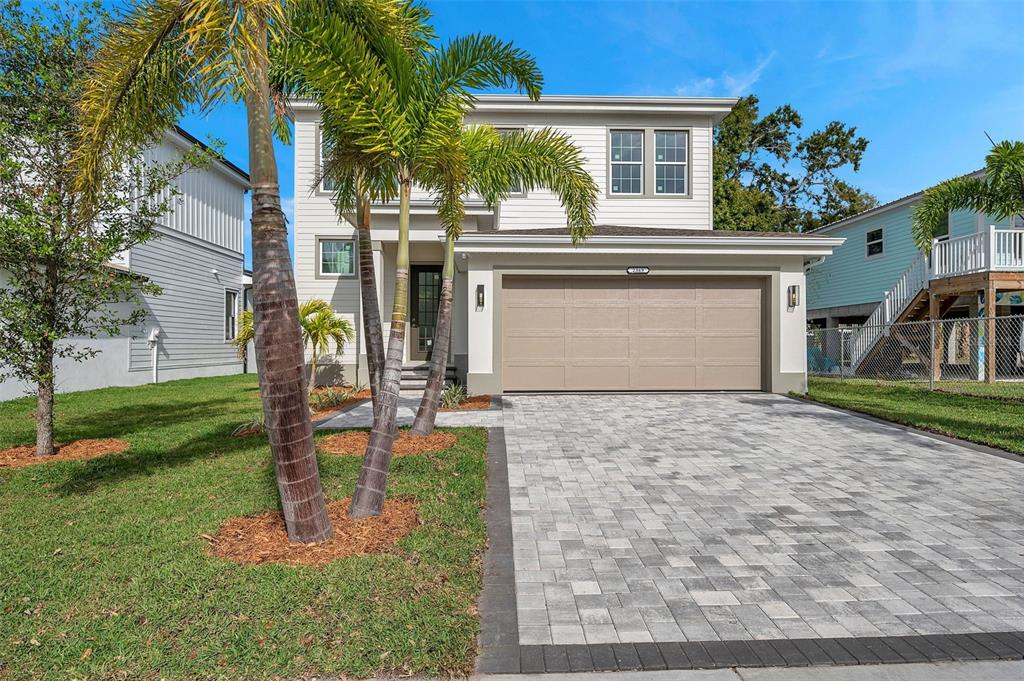 A two-story house with a beige garage, gray paver driveway, and palm trees in front — 2369 BAHIA VISTA STREET, SARASOTA, FL