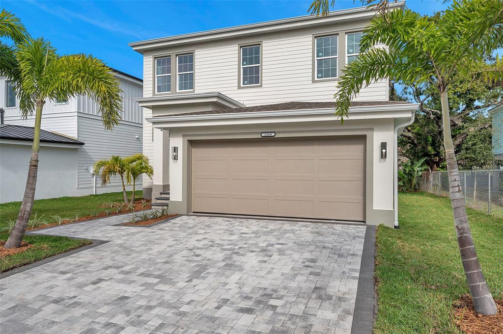 A two-story house with light siding, a tan garage door, and a paved driveway — 2369 BAHIA VISTA STREET, SARASOTA, FL