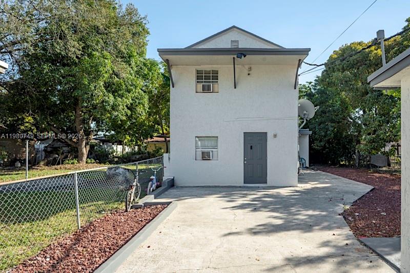 A two-story white stucco building with a gray door stands beside a paved driveway — 2378 NW 60th St, Miami FL 33142, MIAMI, FL