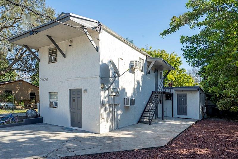 A two-story white stucco building features an exterior metal staircase and a concrete driveway — 2378 NW 60th St, Miami FL 33142, MIAMI, FL