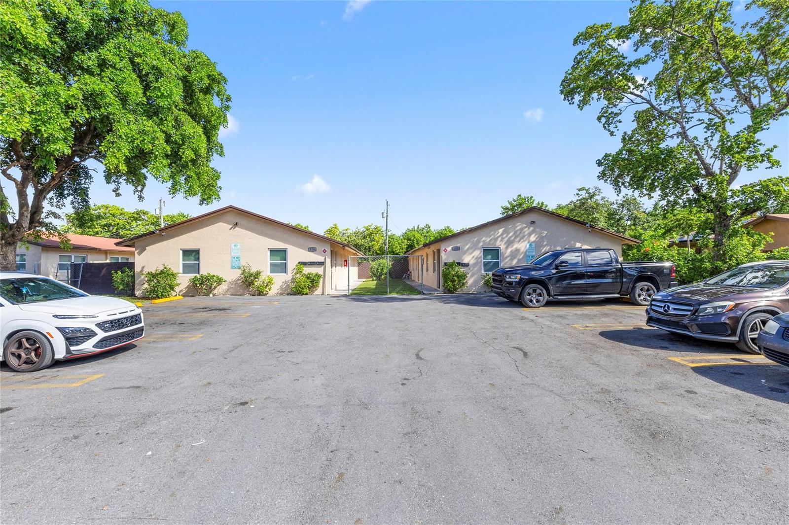 Two single-story apartment buildings face each other across a paved parking lot with trees — 229 NW 12th Court, Pompano Beach FL 33060, POMPANO BEACH, FL