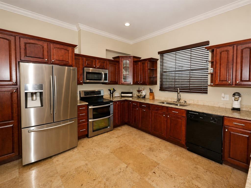 A kitchen with dark wood cabinets, stainless steel appliances, and light-colored stone tile flooring — 3517 HAINES ROAD N, ST PETERSBURG, FL