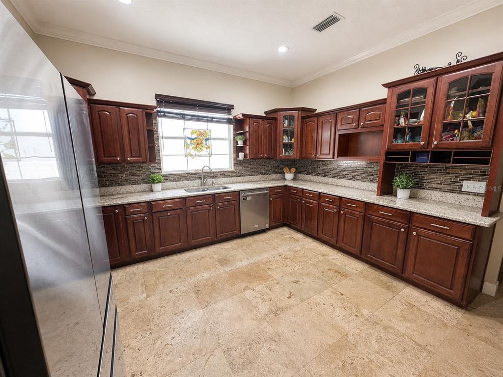 A kitchen with dark wood cabinets, granite countertops, and light-colored stone tile flooring — 3517 HAINES ROAD N, ST PETERSBURG, FL