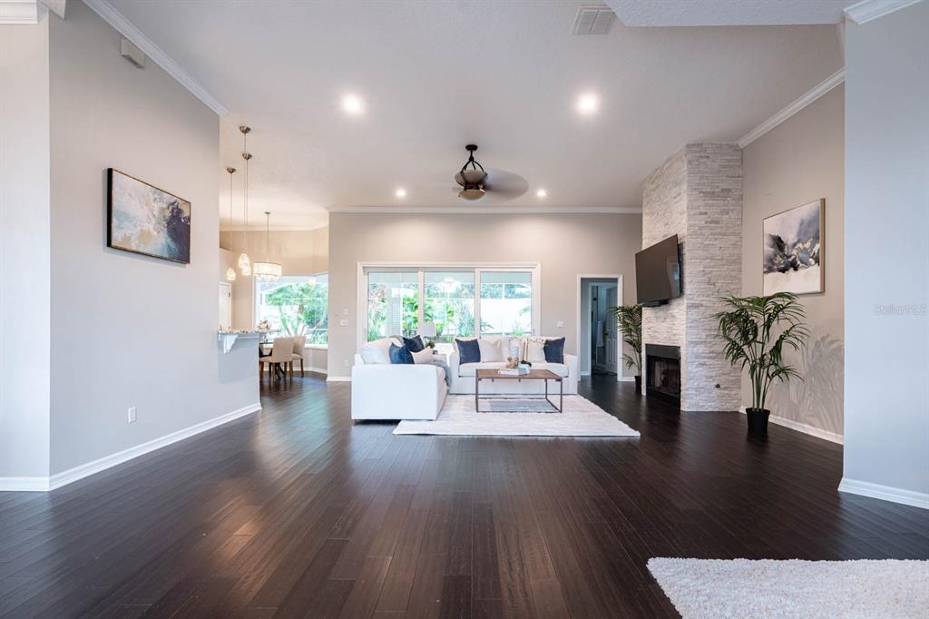 A living room features dark wood floors, a white sectional sofa, and a stone fireplace — 5311 BAY SIDE DRIVE, ORLANDO, FL