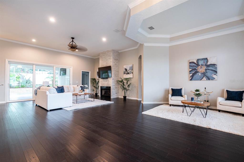 A spacious living room features dark hardwood floors, a stone fireplace, and sliding glass doors — 5311 BAY SIDE DRIVE, ORLANDO, FL