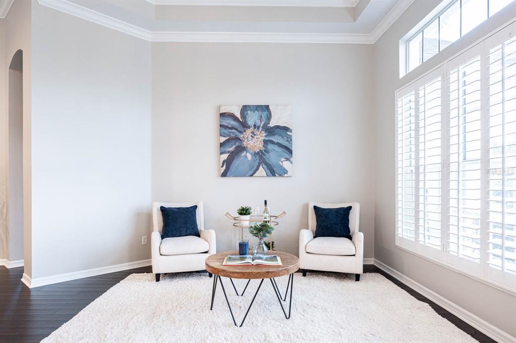 A sitting area features two white armchairs, a round wooden coffee table, and blue wall art — 5311 BAY SIDE DRIVE, ORLANDO, FL