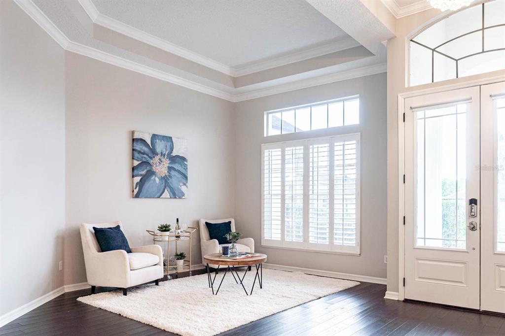 A bright living room features two armchairs, a coffee table, and a large blue floral painting — 5311 BAY SIDE DRIVE, ORLANDO, FL