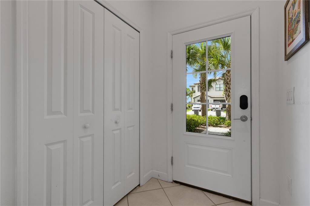 An entryway with white tile floors, a white closet, and a white front door — 15227 SUNNY DAY DRIVE, BRADENTON, FL