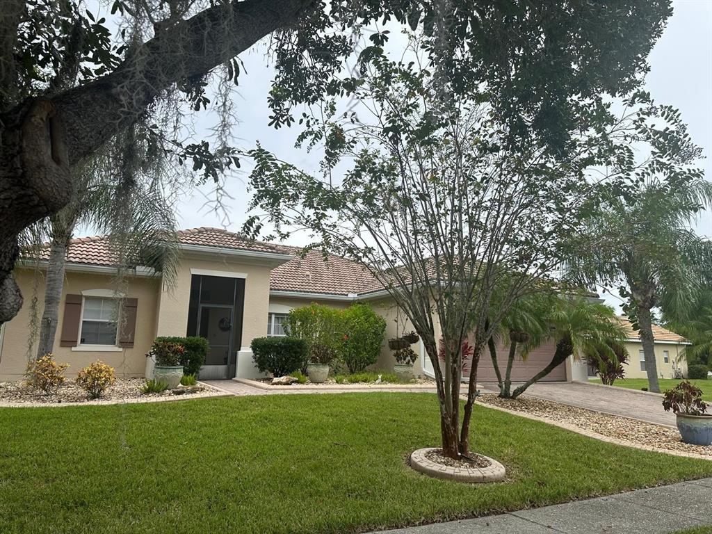 A single-story suburban house with a tiled roof, beige stucco walls, and a landscaped front yard — 4002 BOUGAINVILLEA PLACE, KISSIMMEE, FL