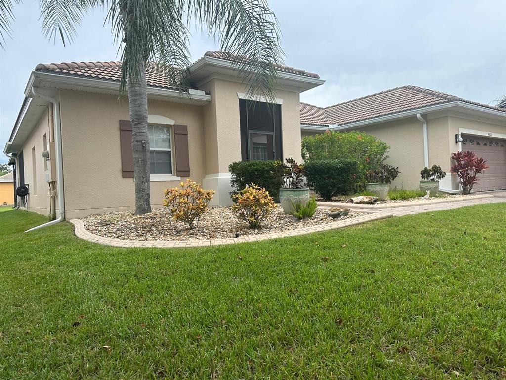 A single-story house with a beige stucco exterior, a tiled roof, and a landscaped yard — 4002 BOUGAINVILLEA PLACE, KISSIMMEE, FL