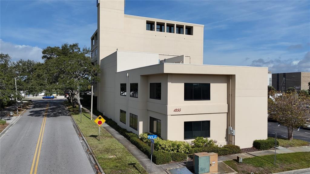 An exterior view of a two-story beige commercial building with dark windows on a corner — 1255 CLEVELAND STREET UNIT 400, CLEARWATER, FL