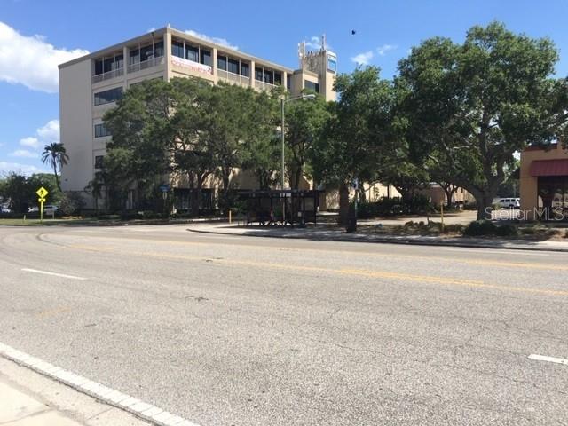 A multi-story office building stands behind a parking lot with trees and a bus stop — 1255 CLEVELAND STREET UNIT 400, CLEARWATER, FL