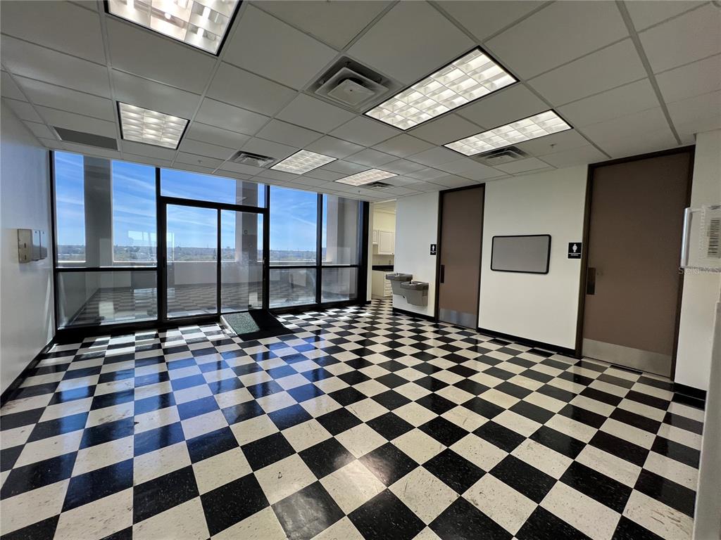 An office room features a black and white checkered floor, drop ceiling, and glass balcony doors — 1255 CLEVELAND STREET UNIT 400, CLEARWATER, FL