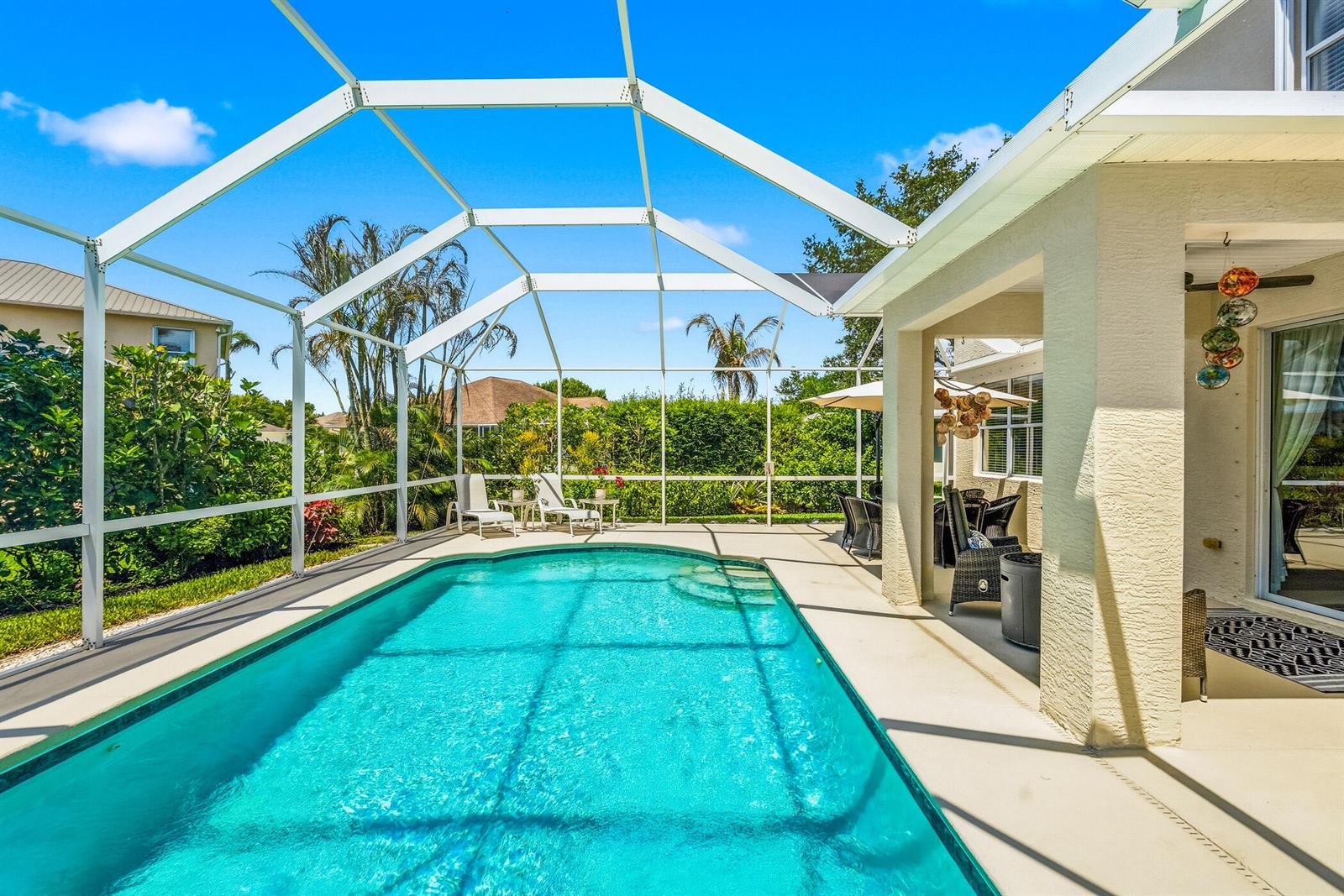 A swimming pool sits inside a screened-in lanai next to a covered patio area — 6455 36th Lane, Vero Beach FL 32966, VERO BEACH, FL