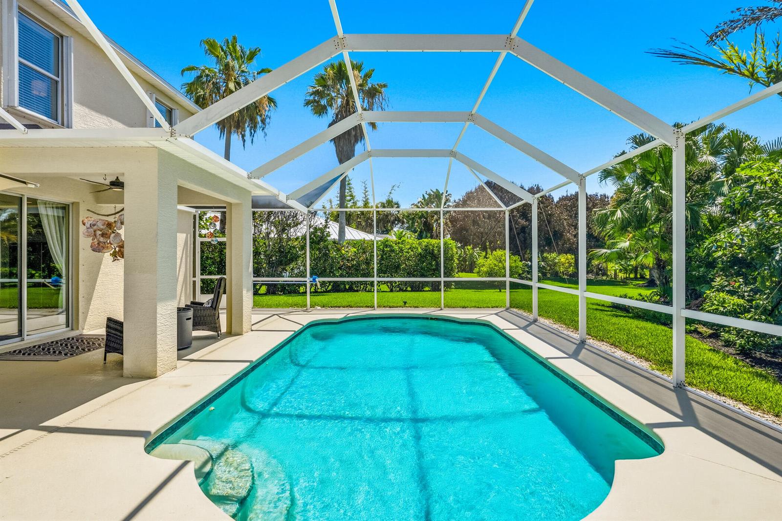 A swimming pool with a screened enclosure sits on a patio next to a house — 6455 36th Lane, Vero Beach FL 32966, VERO BEACH, FL