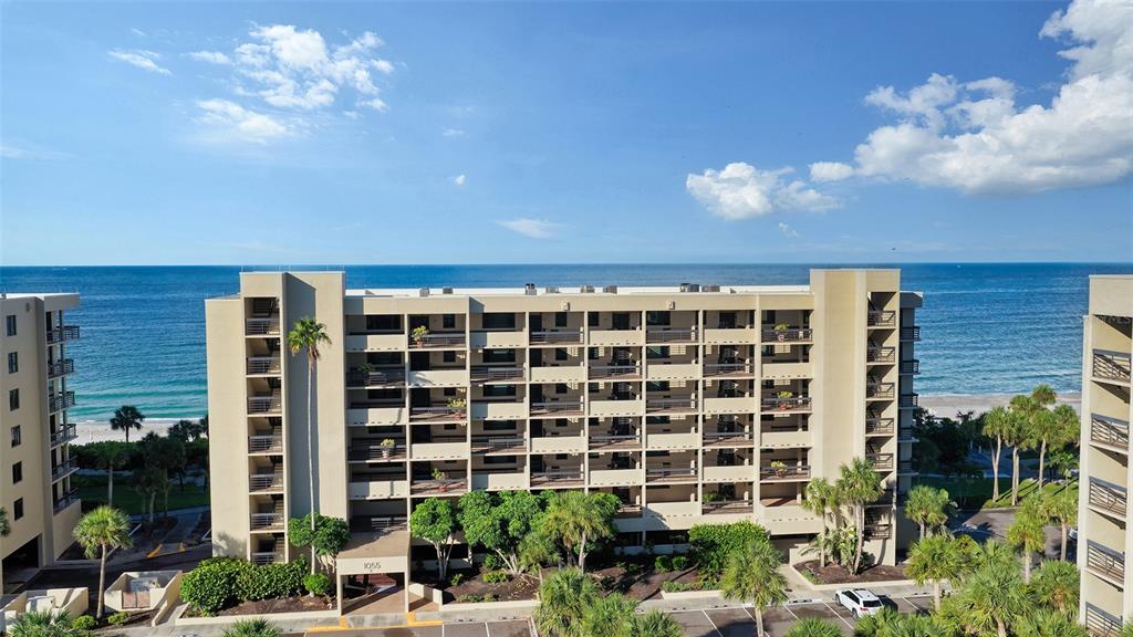 An aerial view shows a multi-story apartment building situated directly along a sandy beach — 1055 GULF OF MEXICO DRIVE UNIT 504, LONGBOAT KEY, FL