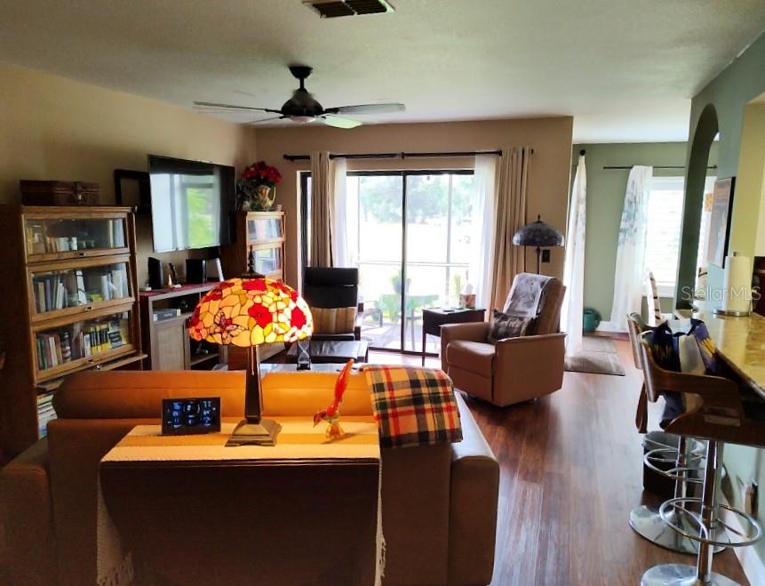 A living room features a leather sofa, a stained-glass lamp, and a sliding glass door — 3549 INDIGO POND DRIVE UNIT 2, PALM HARBOR, FL