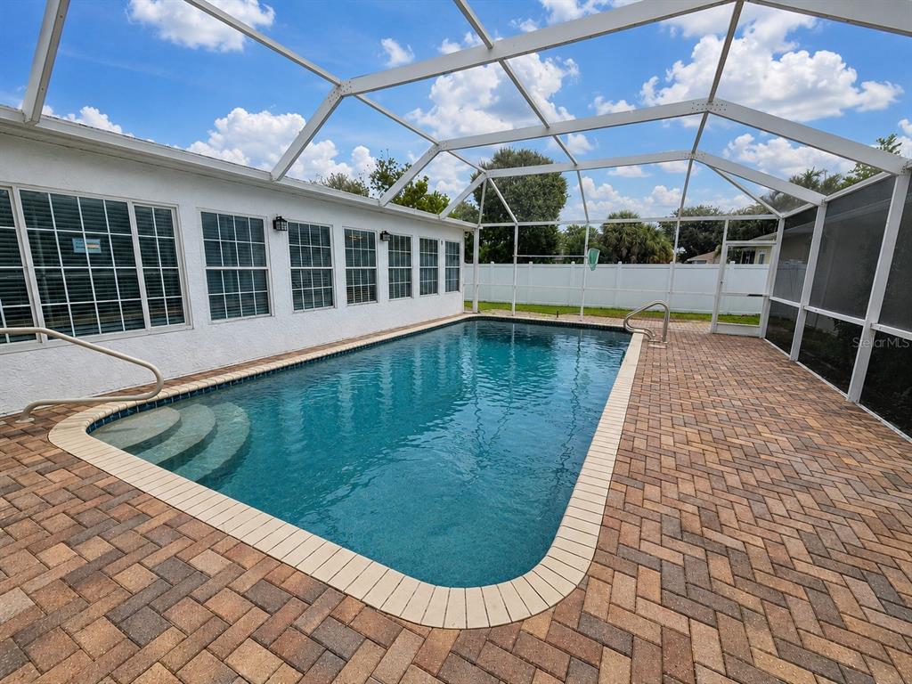 A screened-in patio features a brick paver floor, a swimming pool, and multiple outdoor chairs — 2130 PINEHURST STREET, SARASOTA, FL