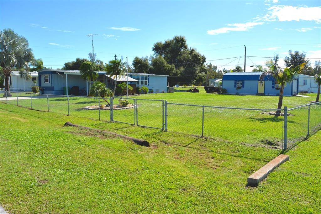 A fenced yard features a light blue mobile home and a smaller blue outbuilding — 15266 CIRCLE DRIVE, PUNTA GORDA, FL