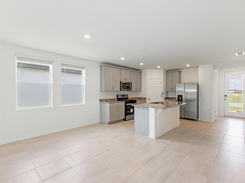A kitchen with gray cabinets, granite countertops, stainless steel appliances, and tile flooring — 4530 EAGLE PERCH COURT, ST CLOUD, FL