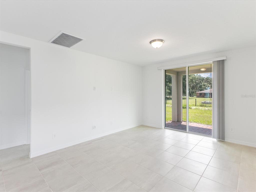 A bright room with white walls, tile flooring, and a sliding glass door to a patio — 4530 EAGLE PERCH COURT, ST CLOUD, FL
