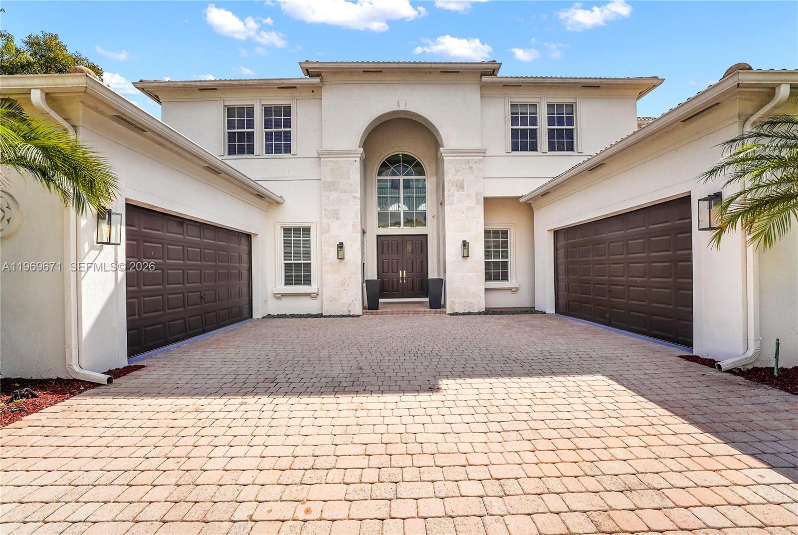 A two-story house with a paved driveway, two garage doors, and a central arched entryway — 12486 World Cup Ln, Wellington FL 33414, WELLINGTON, FL