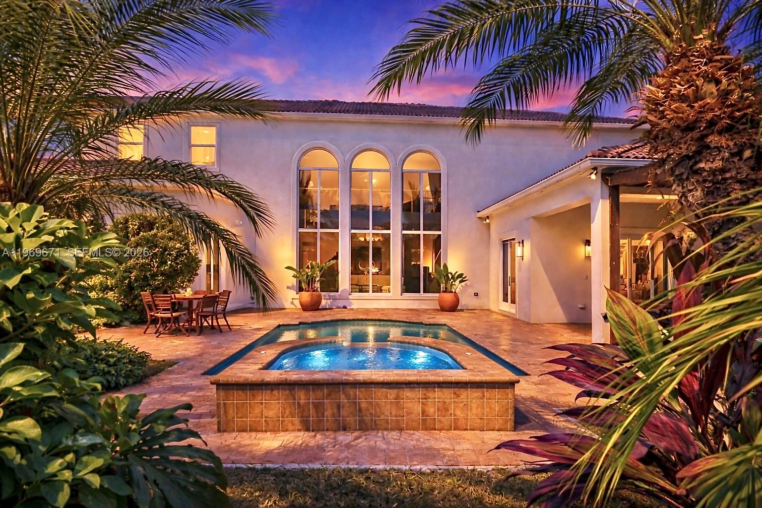 A backyard patio features a swimming pool with an integrated spa and arched windows — 12486 World Cup Ln, Wellington FL 33414, WELLINGTON, FL