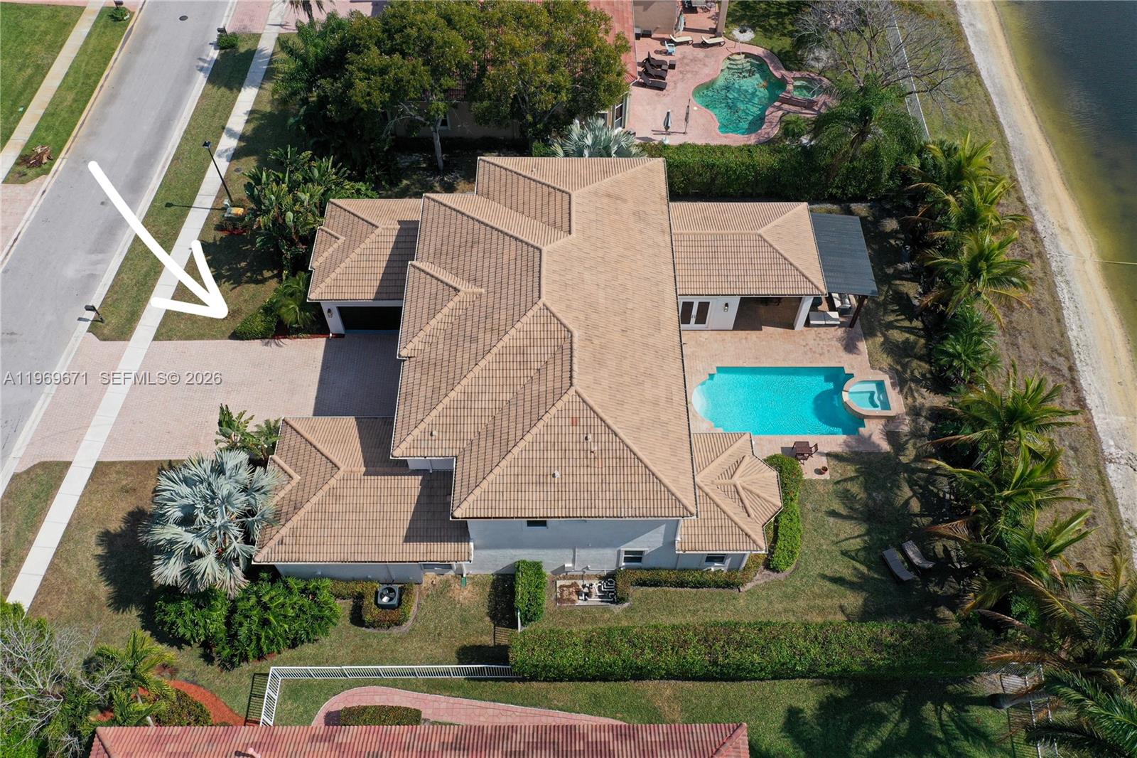 An aerial view shows a house with a tiled roof, pool, and paved driveway — 12486 World Cup Ln, Wellington FL 33414, WELLINGTON, FL