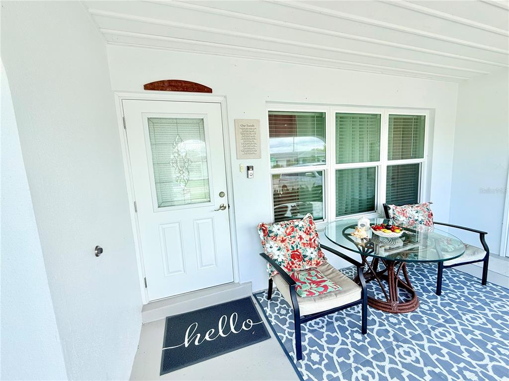 A covered front porch features a white door, a glass-topped table, and two chairs — 8509 LA BOCA AVENUE, NORTH PORT, FL