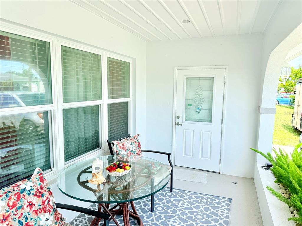A covered front porch features a glass-topped table, floral chairs, and a white entry door — 8509 LA BOCA AVENUE, NORTH PORT, FL