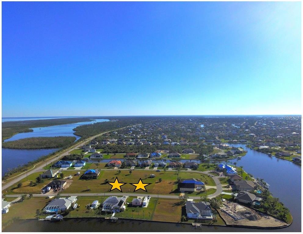 An aerial view shows two adjacent vacant residential lots marked with yellow stars in a neighborhood — 15443 ALCOVE CIRCLE, PORT CHARLOTTE, FL