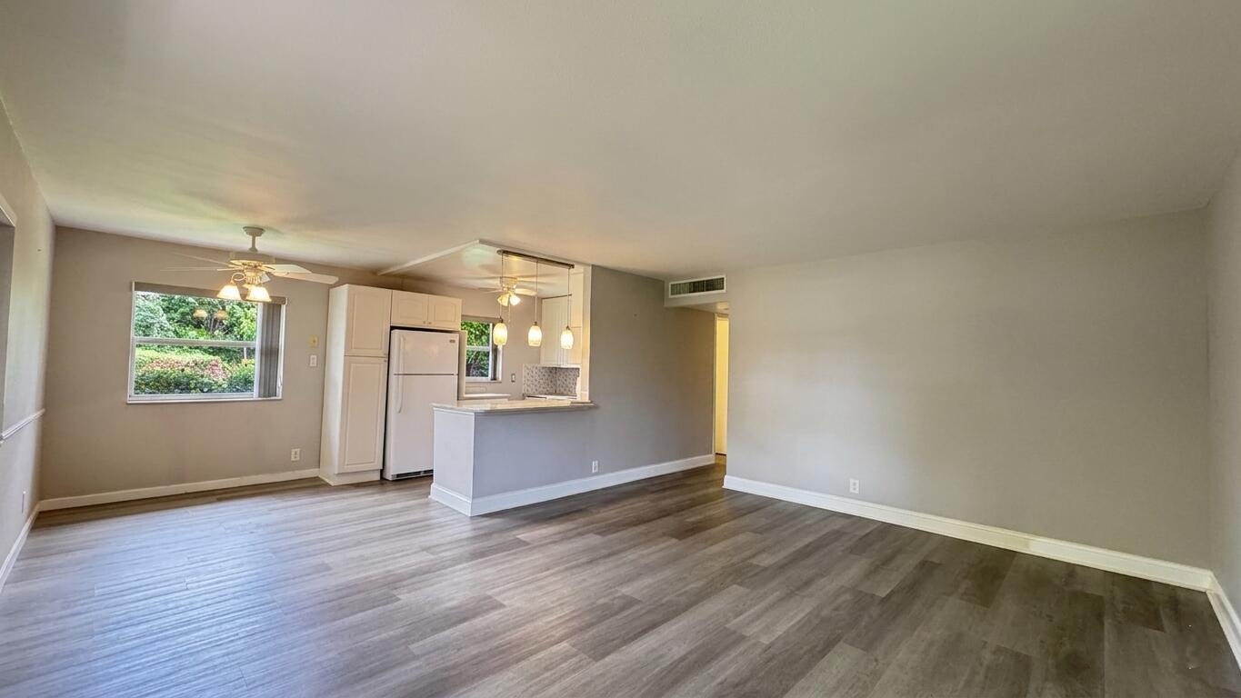 An open-concept living area features light gray walls, wood-look flooring, and a kitchen with white cabinets — 220 Seville J, Delray Beach FL 33446, DELRAY BEACH, FL