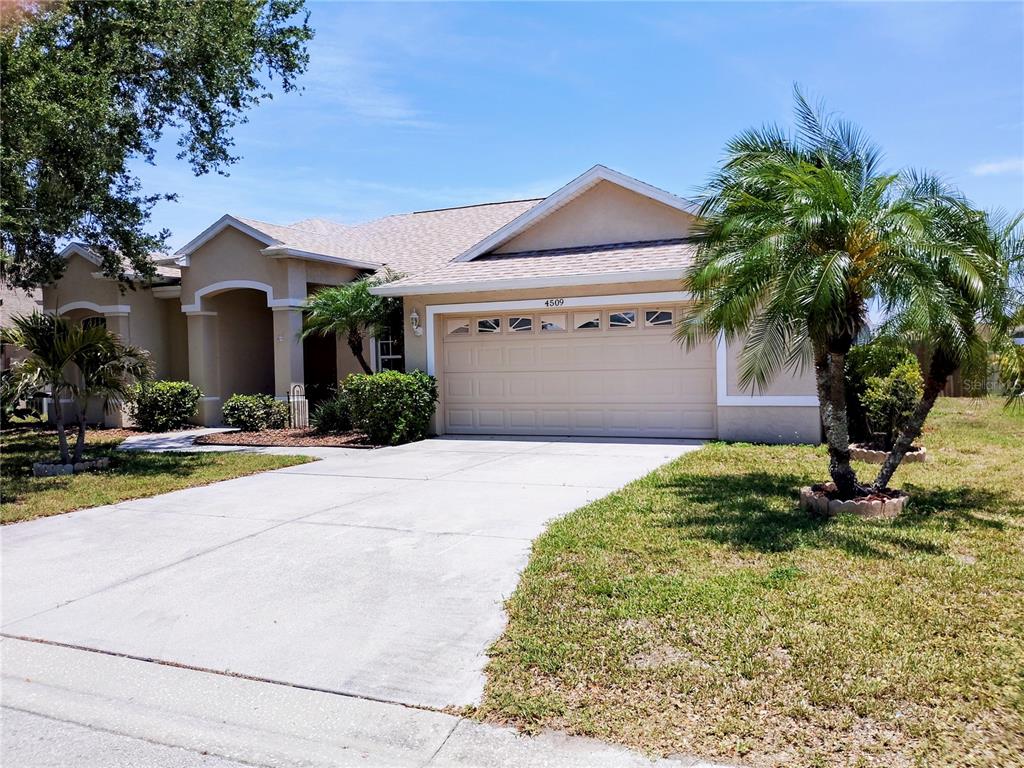 A single-story house with a beige stucco exterior, a two-car garage, and a palm tree — 4509 30TH LANE E, BRADENTON, FL